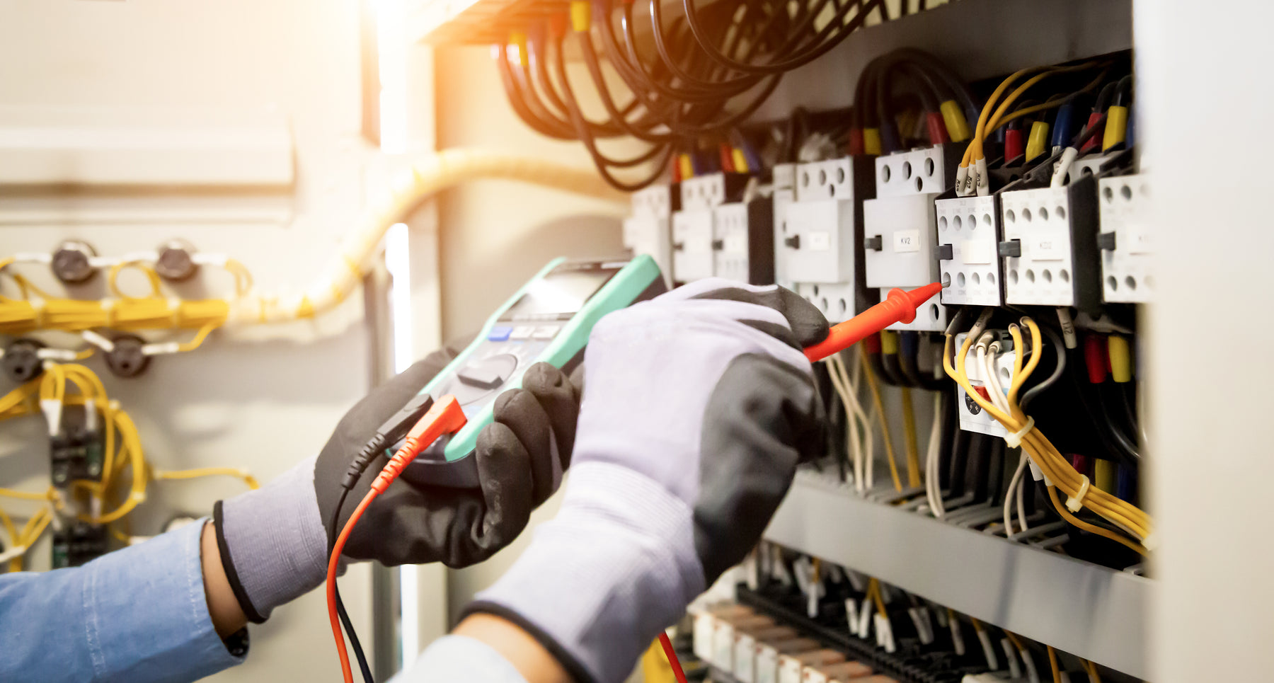 Technician checking system voltage with a multimeter at a distribution panel