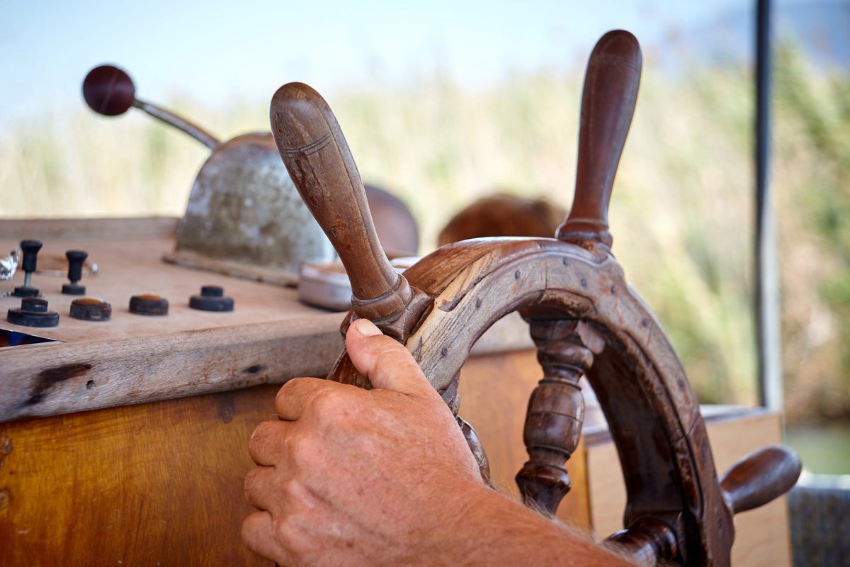 Close-up of a sailor's hand on a sailboat steering wheel