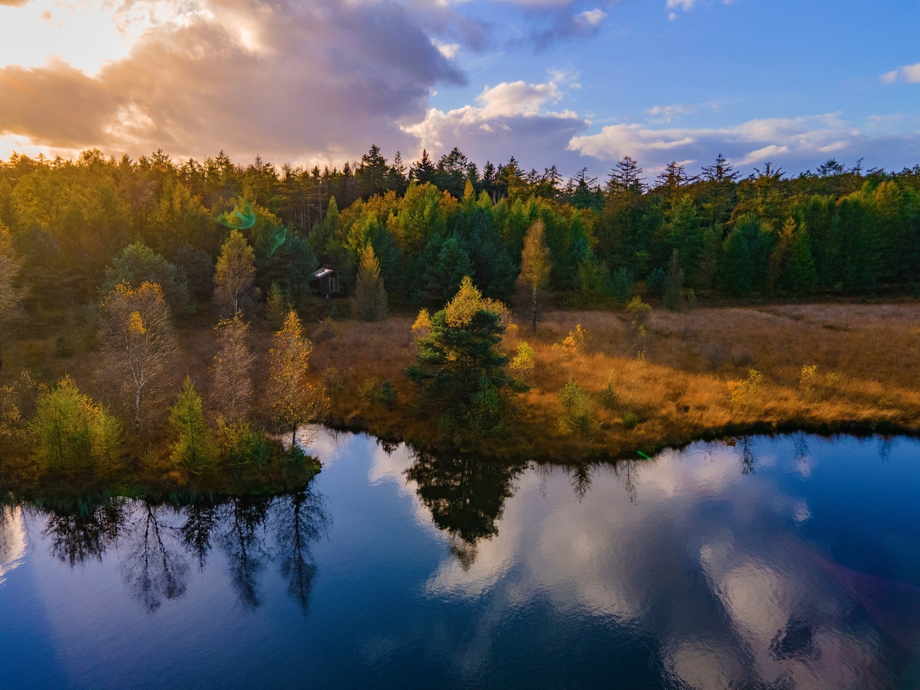 Off grid wooden cabin surrounded by colorful autumn forest