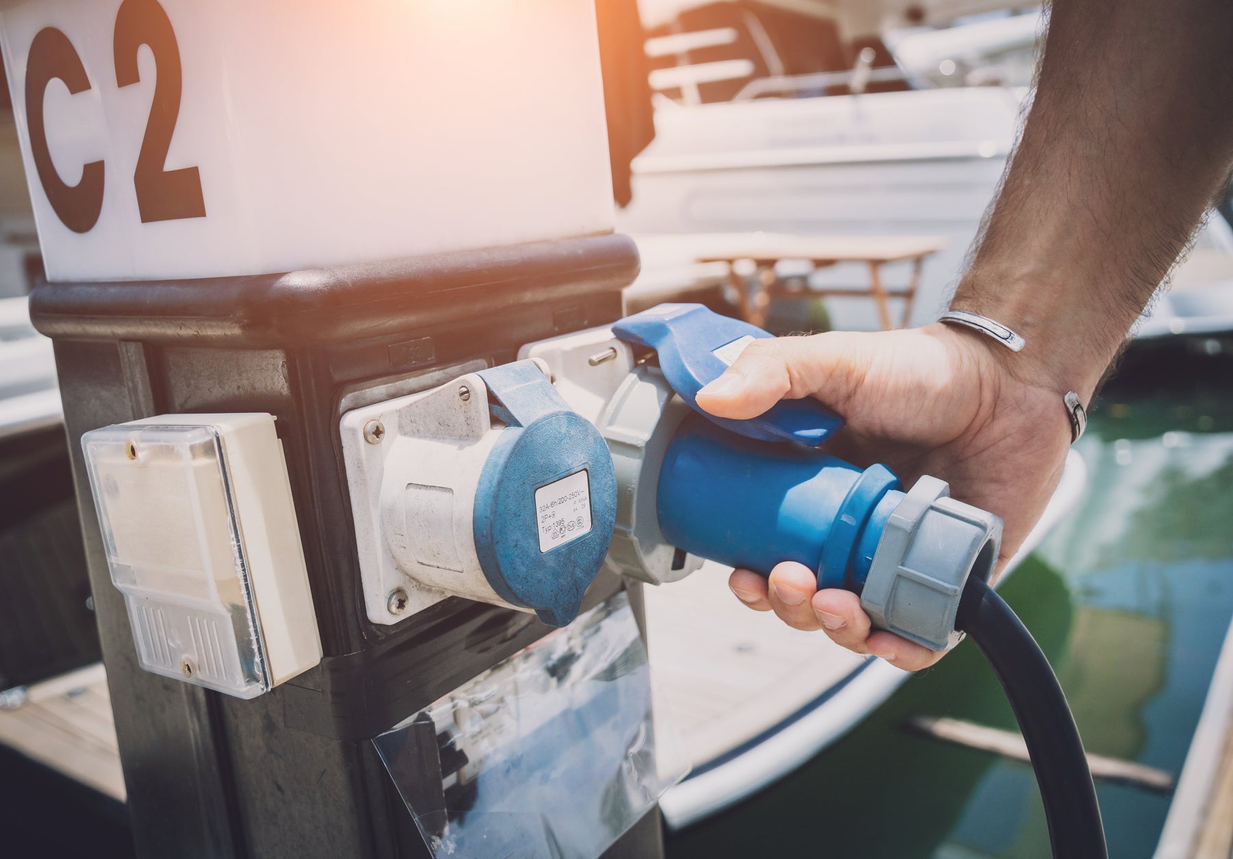 Boater connecting shore power from a marina pedestal to his yacht