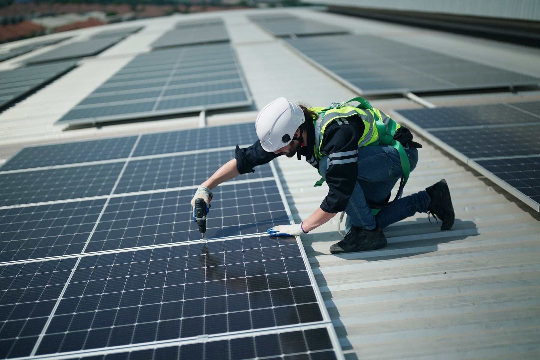 Installer securing a solar panel with mounting hardware during installation