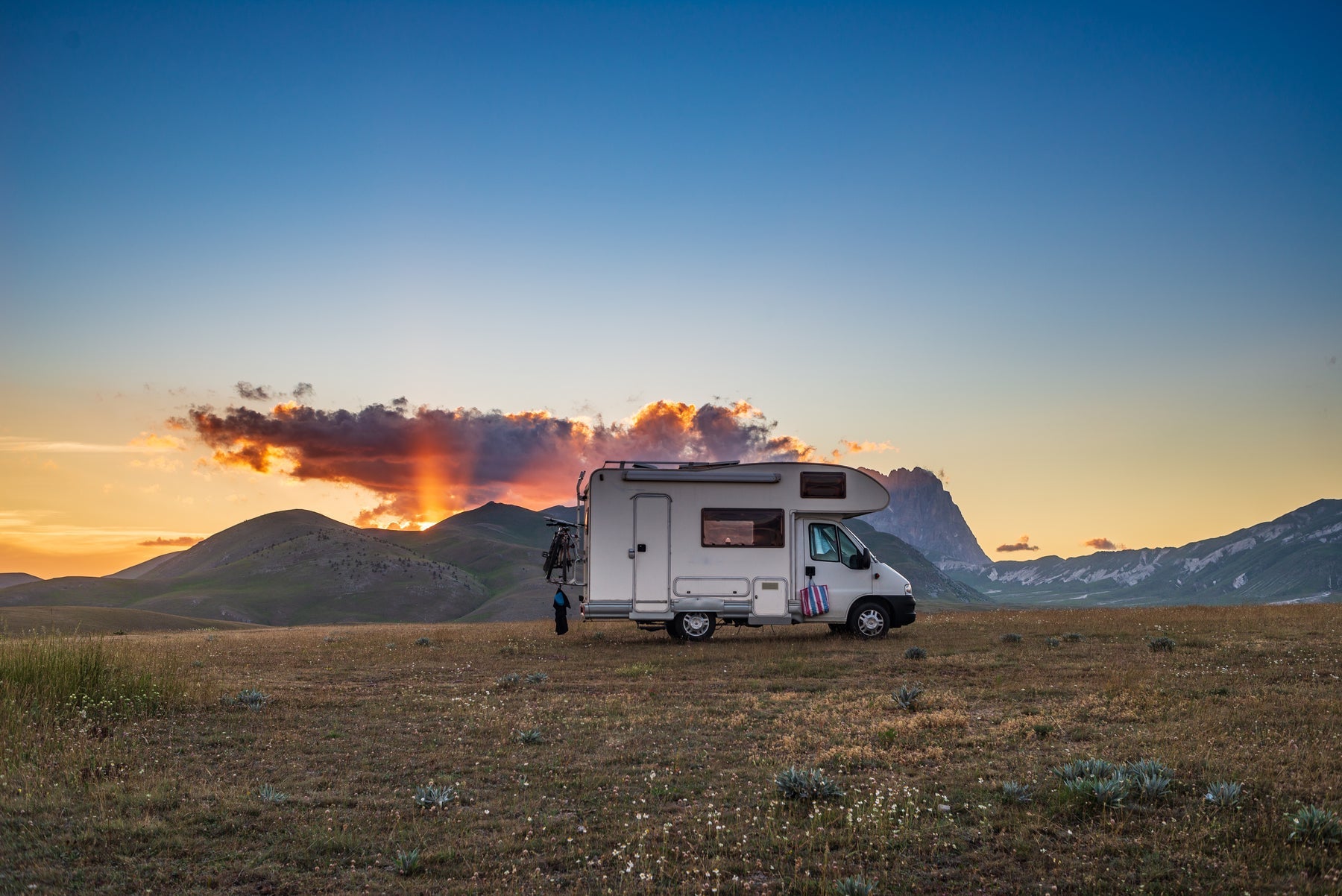 Camper van boondocking in remote highlands under a dramatic sunset