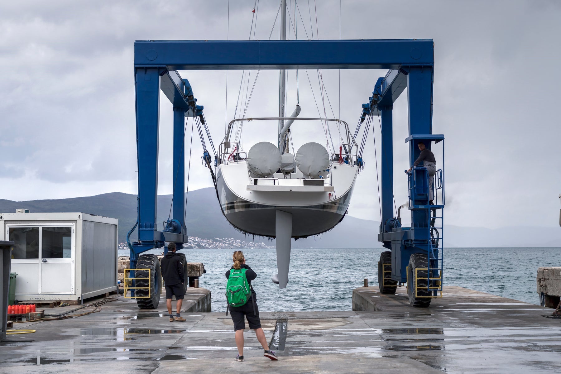 Sailboat being lifted by a marina boatyard crane for seasonal maintenance